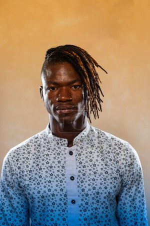 Studio portrait of a confident African man with stylish dreadlocks wearing a floral patterned shirt, exuding elegance and cultural identity