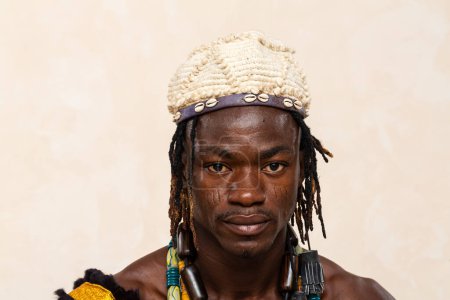 Nahaufnahme eines afrikanischen Mannes, der traditionelle Verzierungen präsentiert, mit einem Stirnband aus Kaurimuscheln und einer lebendigen Perlenkette, die sein kulturelles Erbe widerspiegelt