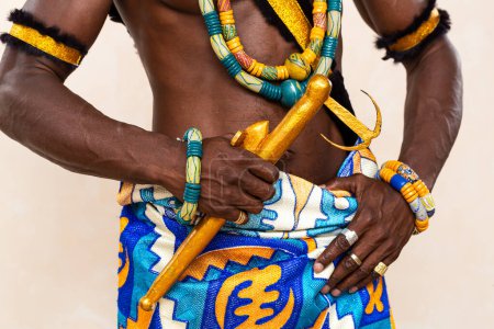 Nahaufnahme der lebendigen Kleidung und des detaillierten Schmucks eines traditionellen afrikanischen Mannes, der die leuchtenden Farben und komplizierten Muster hervorhebt, die symbolisch für seine kulturelle Identität sind