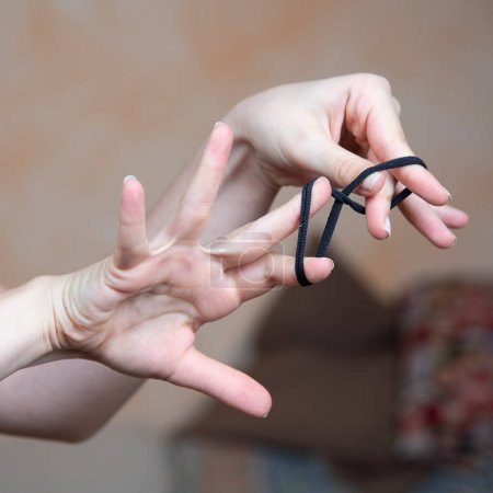 A close-up shot of hands skillfully tying a black elastic hair band
