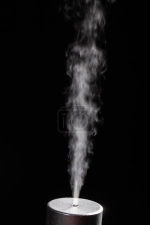 Fesselndes Bild eines stetigen Rauchstroms, der von einem zylindrischen Objekt ausgeht, isoliert vor einem dunklen Hintergrund, der wissenschaftlichen oder industriellen Tests ähnelt