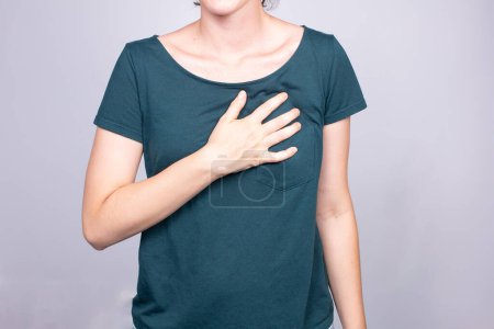 Una imagen cercana de una mujer que sostiene su estómago con dolor, capturando el síntoma común de gastritis, la inflamación del revestimiento del estómago