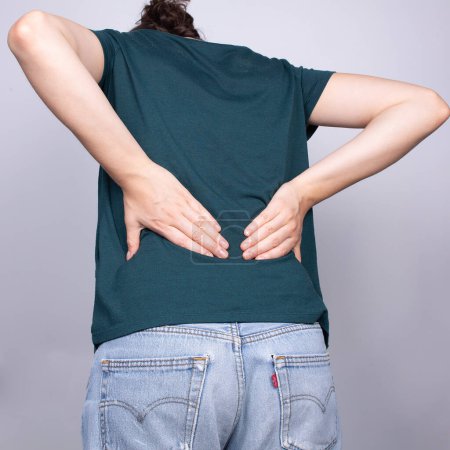 La imagen se centra en la parte inferior de la espalda de una persona, ya que experimenta el dolor típico de una hernia discal, una condición espinal común
