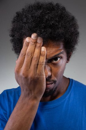 An intense image capturing a man pressing his hand against his forehead, possibly indicating eye strain, a migraine, or deep concentration