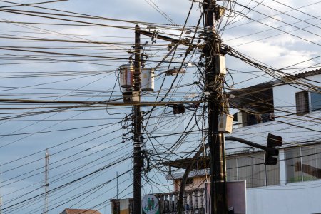 un réseau enchevêtré de fils électriques couronne un pôle urbain, mettant en valeur l'infrastructure énergétique complexe et chaotique de la ville