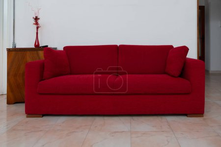 ein stilvolles rotes Sofa bietet einen Farbtupfer gegen ein minimalistisches Dekor, das zeitgenössisches Wohndesign widerspiegelt