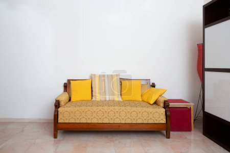 ein klassisches Holzsofa mit gelben Kissen bringt Wärme in eine gemütliche Ecke und verströmt Vintage-Charme und Komfort