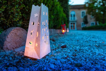 Sanft beleuchtete Papierlaternen mit Sternen und Monden schaffen eine magische Atmosphäre auf einem dämmerigen Gartenweg