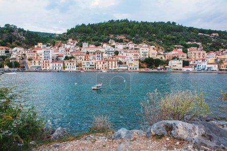 a scenic seaside village cascades down the hillside, its colorful facades reflecting in the calm waters below