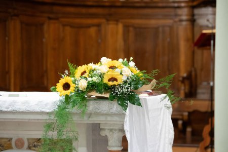 a beautiful floral centerpiece adorns the church altar, featuring bright sunflowers and delicate white roses, symbolizing joy and purity for a wedding celebration