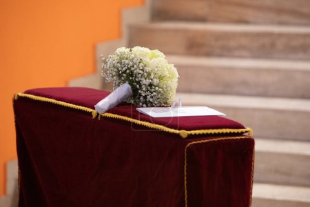 Foto de Elegante ramo de novia descansa en un podio de terciopelo, esperando la ceremonia de la boda con escaleras en el fondo - Imagen libre de derechos