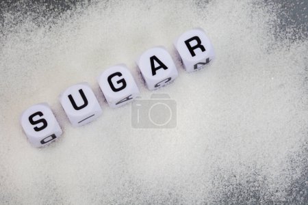 Photo for Sugar written in letter dice on white sugar granules - Royalty Free Image