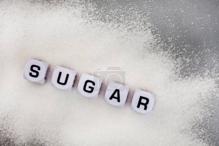 Photo for Sugar written in letter dice on white sugar granules - Royalty Free Image