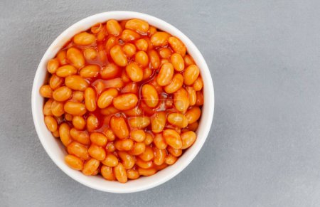 Flat lay of baked beans in round bowl on grey surface