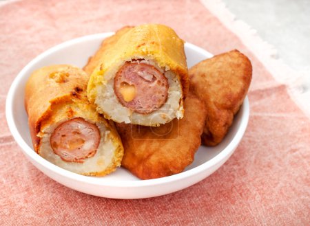Traditional South African Russian sausage Sputnik or deep fried mash covered sausage on wooden board with traditional printed cloth