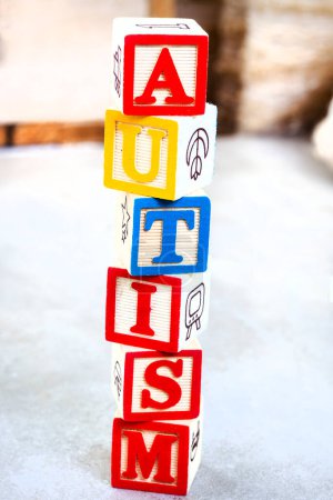 Autism spelled out in kids building blocks on mottled grey