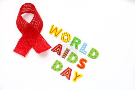 Téléchargez les photos : Journée mondiale des aides écrites en lettres colorées sur fond blanc avec ruban de sensibilisation rouge - en image libre de droit
