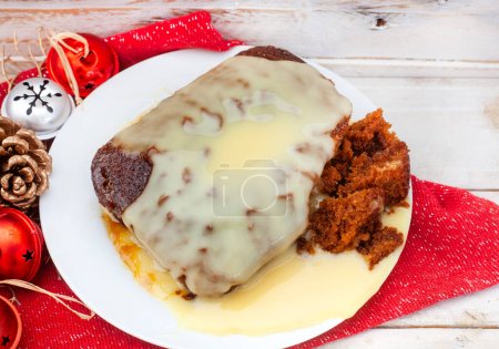 Téléchargez les photos : Pudding Malva traditionnel sud-africain avec crème anglaise sur table de Noël rustique. Un dessert préféré toute l'année. - en image libre de droit
