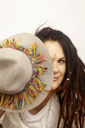 Téléchargez les photos : Femme bohème alternative avec dreadlocks. Portrait ludique avec chapeau coloré - en image libre de droit