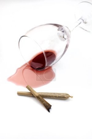 Téléchargez les photos : Marijuana joint avec du vin rouge renversé sur blanc - en image libre de droit