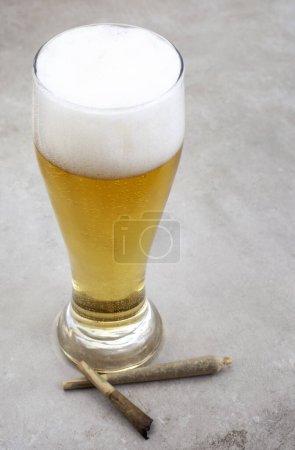 Téléchargez les photos : Joint de marijuana avec verre de bière sur une surface grunge grise - en image libre de droit