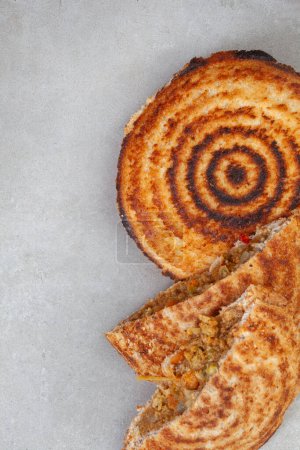 Jaffle, an old school toasted sandwich, filled with savory mince. Grey backdrop, copy space