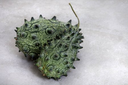 African cucumber, Kiwani fruit or horned melon on mottled grey with copy space