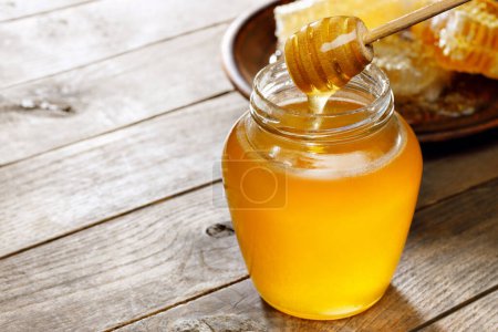 Foto de Tarro de vidrio de miel con panal en mesa de madera - Imagen libre de derechos
