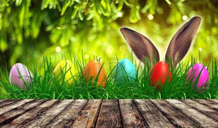 Photo for Empty rustic wooden table with easter egg and blurred green nature background. Abstract blurry Easter scene with bokeh and warm sunlight. Concept banner for products display - Royalty Free Image