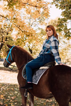Photo for A woman sits on top of a horse. Horse riding in the autumn park. High quality photo - Royalty Free Image
