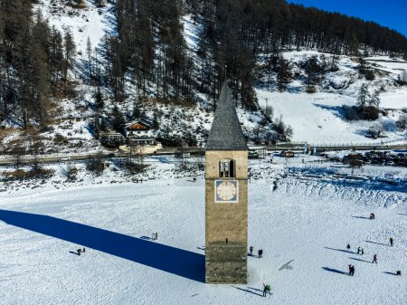 Winterlandschaft in den Alpen mit dem berühmten versunkenen Kirchturm in Reschensee an der Grenze zwischen Südtirol (Italienische Alpen) und Österreich.