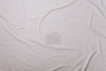 Top view of wrinkles on beige spotted bed sheet. Bed linen texture. Copy space.