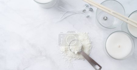 ingredients for candle making , soy wax flakes, candles, wicks on light marble background, blank label for design mockup