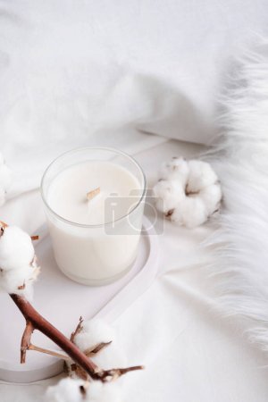 Photo for Soy wax aroma candle in white jar on bed with cotton branch. Candle mockup design. Mockup soy wax candle in natural style. - Royalty Free Image
