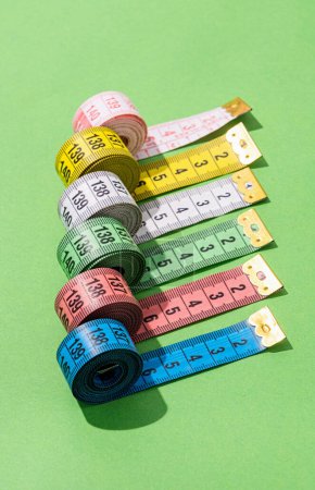 Foto de Concepto de dieta. cintas de medición de colores vista superior sobre fondo verde brillante, disposición plana, patrón - Imagen libre de derechos