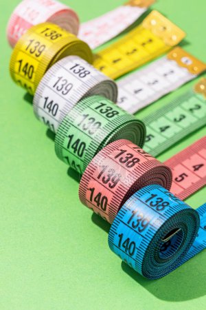 Foto de Concepto de dieta. cintas de medición de colores vista superior sobre fondo verde brillante, disposición plana, patrón - Imagen libre de derechos