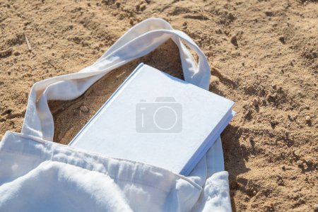 Mockup shopper handbag and book, beach sand background. Top view copy space shopping eco reusable bag.