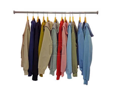 Row of different colorful youth cashmere sweaters and hoodies, sweatshirts and on a clothes rack. Isolated on white background. Multicolored hoodies on hangers in a sports store, clothing concept.