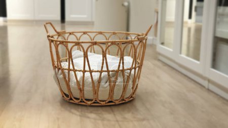 Wicker basket made of natural rattan woven with cushion inside. Selective focus with blurred dressing room decor background. Handmade storage rattan basket stylish interior item eco design.