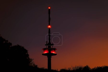 Photo for TV tower in forest, night shot at golden hour with red air traffic control lighting. Orange blue night sky. Taken in Bovenden near Goettingen. - Royalty Free Image
