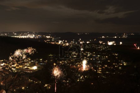 Téléchargez les photos : Plan nocturne d'un village avec des feux d'artifice de la Saint-Sylvestre avec plusieurs fusées de vue d'oiseau - en image libre de droit