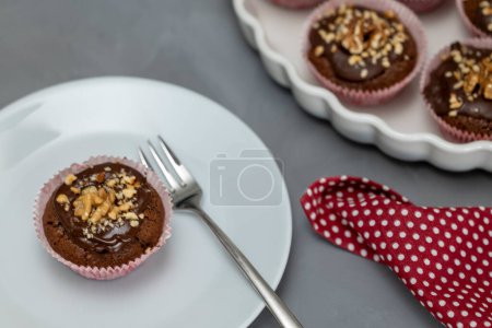 Photo for Chocolate walnut muffins served on plate. With cake plate with more muffins in background - Royalty Free Image