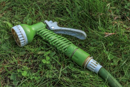A green gun for watering plants in the garden with a hose