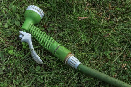 A green gun for watering plants in the garden with a hose