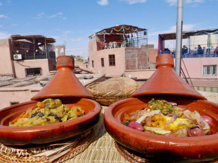 Téléchargez les photos : Tajine, ragoût marocain à cuisson lente servi et cuit dans une marmite en terre cuite, sur le toit-terrasse à Marrakech, Maroc. Photo de haute qualité - en image libre de droit