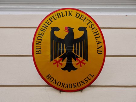 Téléchargez les photos : Gros plan du panneau jaune avec le manteau d'aigle de la République fédérale d'Allemagne sur le bâtiment du consulat honoraire à Bolzano, Italie, 14.05.2023. Photo de haute qualité - en image libre de droit