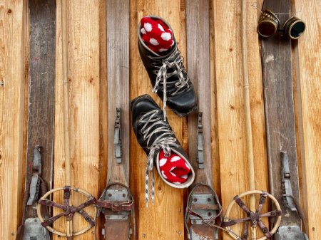 Close up of old leather hiking boots and wooden skis on facade of mountain hut. Alpine decor. High quality photo