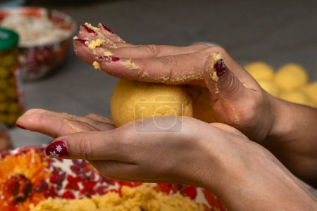 Frauenhände mit Mais-Teigkugel zur Zubereitung von hallaca oder tamale