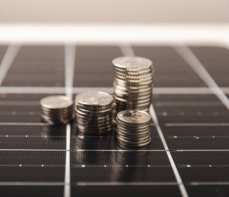 Sonnenkollektoren und Münzen. Konzept der Einsparung von Geld und sauberer Energie. Ökonomische Vorteile erneuerbarer Energien.