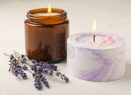 Aromatherapy concept, candle with lavender flowers.Soy candles with lavender scent. Candles on a white texture background. Place for text. Place for copying. Spa candles with a pleasant aroma.